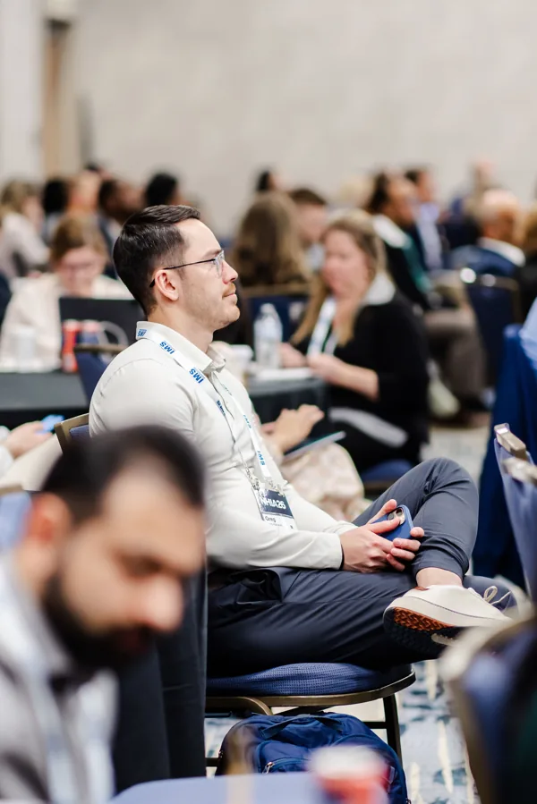 An attendee reads on his phone while seated in a conference session.
