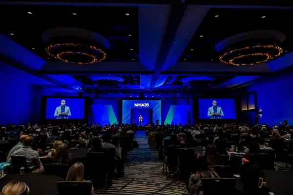 The opening general session stage with twin projection screens and a full audience.