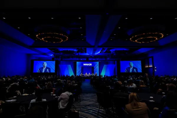 The general session ballroom from the back of the room, screens lit and every seat filled.