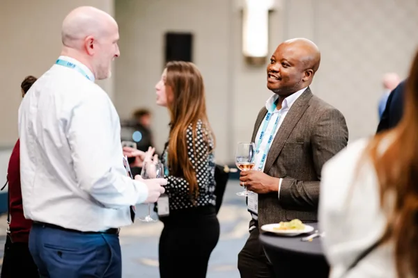 Three attendees stand talking together at a networking event.