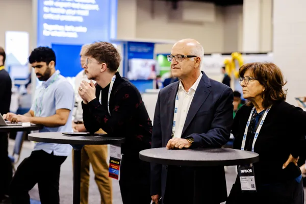 Attendees talk around a high-top table on the expo floor.