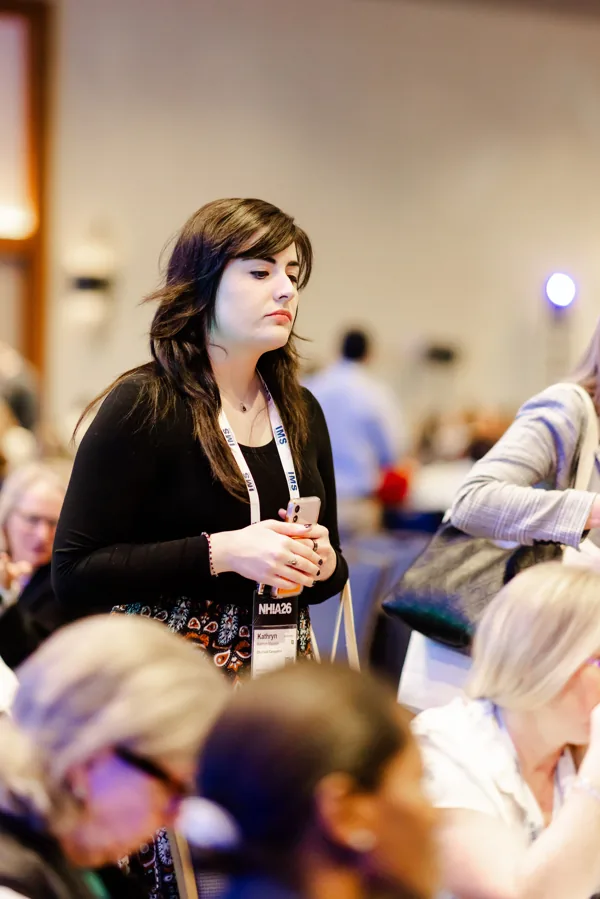 An attendee checks her phone at a conference reception.
