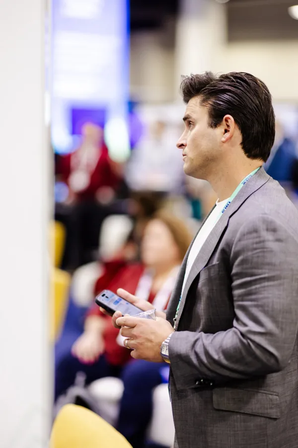 An attendee stands in a session room checking his phone.